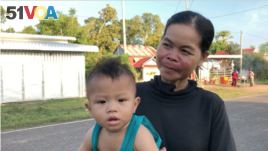 Sim Lat, 40, carries her nephew Ham Ya Oudom on a walk while waiting for his mom to come back from work, at Svay Ta Yean commune, Svay Rieng province, Cambodia, Oct. 11, 2019.
