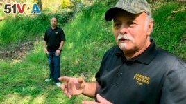 In this Sept. 20, 2018 photo, Dennis Parada, right, and his son Kem Parada stand at the site of the FBI's dig for Civil War-era gold in Dents Run, Pennsylvania. (AP Photo/Michael Rubinkam)
