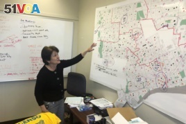 In this Nov. 22, 2019, photo, Detroit 2020 Census Campaign executive director Victoria Kovari looks over a Detroit map showing city neighborhoods that were under-counted in the 2010 census. (AP Photo/Corey Williams)
