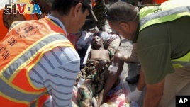 United Nations and other workers assist a young wounded man after he and others were airlifted to Mogadishu for treatment, following Sunday's attack on restaurants in the city of Baidoa, at the airport in Mogadishu, Somalia, Feb. 29, 2016.  