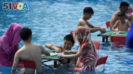 People play mahjong as they sit in water at a water park on a hot day in Chongqing, China August 2, 2017. 