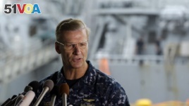 Vice Adm. Joseph Aucoin, commander of the U.S. 7th Fleet, speaks during a press conference, with the damaged USS Fitzgerald in the background at the U.S. Naval base in Yokosuka, southwest of Tokyo, June 18, 2017.