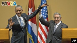 Cuban President Raul Castro, right,  lifts up the arm of President Barack Obama at the conclusion of their joint news conference at the Palace of the Revolution, Monday, March 21, 2016, in Havana, Cuba. (AP Photo/Ramon Espinosa)