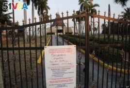 A sign hanging on a locked gate in front of the Ermita de la Caridad church in Miami indicates that the church is closed during the new coronavirus pandemic, Thursday, April 9, 2020.