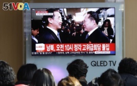 People watch a TV screen showing South Korean Unification Minister Cho Myoung-gyon, left, meets with the head of North Korean delegation Ri Son Gwon