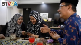 Tengku Shawal, a royal descendant, talks as his daughter Tengku Puteri (L) and his sister Tengku Intan (C) reminisce over old family photos at Intan's home in Singapore August 21, 2020. (REUTERS/Edgar Su)