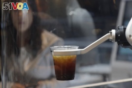 In this May 22, 2019, photo, a customer waits for a coffee in front of a robot named b;eat after placing an order at a cafe in Seoul, South Korea. (AP Photo/Lee Jin-man)