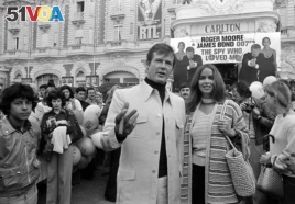 FILE - In this May 20, 1977 file photo, actor Roger Moore, alias British secret agent James Bond, is accompanied by co-star Barbara Bach as they arrive for the screening of 