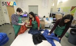 In this Friday, Dec. 21, 2018, photo, from left, Rebecca Schaechter, Nicole Herron and Rachel Herron fold and sort donated clothes at Treehouse, a nonprofit organization in Seattle that serves the needs of children in the foster-care system. The charity w