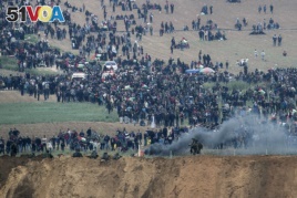 Israeli soldiers stand as Palestinian protesters gather on the Israel Gaza border, Friday, March 30, 2018.