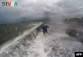 A resident walks past waves spilling over a wall onto a coastal road in the city of Legaspi in Albay province, south of Manila on December 14, 2015, as typhoon Melor approaches the city. 