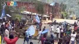 A still image taken from a video shot on October 1, 2017, shows protesters waving Ambazonian flags in front of road block in the English-speaking city of Bamenda, Cameroon. 