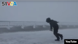 Video Screenshot of man getting blown around in strong winds