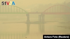 A resident rides a motorcycle on the haze-shrouded Betrix bridge in Sarolangun, on Indonesia's Jambi province, Oct. 7, 2015.