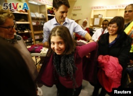 Canada's Prime Minister Justin Trudeau helps a young Syrian refugee try on a winter coat after she arrived with her family from Beirut at the Toronto Pearson International Airport in Mississauga, Ontario, Canada December 11, 2015. (REUTERS/Mark Blinch)