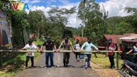 In this April 24, 2020, photo, provided by the Indigenous People Alliance of the Archipelago, indigenous peoples from the Buntao' community in Indonesia's North Toraja regency in South Sulawesi Province use a wooden barrier to block off their village. (AMAN via AP)