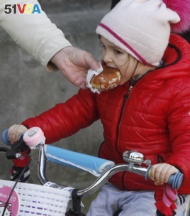 A little girl indulges in Poland's tradition of eating jam-filled doughnuts, or Paczki, in Warsaw, Poland, Feb. 27, 2014.