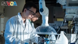 Rice postdoctoral researcher Chuan Xia, left, and chemical and biomolecular engineer Haotian Wang, adjust their electrocatalysis reactor to produce liquid formic acid from carbon dioxide. (Photo by Jeff Fitlow/Rice University's Brown School of Engineering