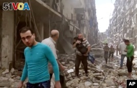 FILE - Image made from video and posted online from Validated UGC, a man carries a child after airstrikes hit Aleppo, Syria.