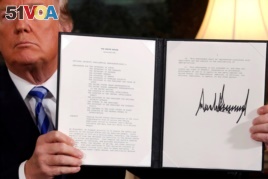 U.S. President Donald Trump holds up a proclamation declaring his intention to withdraw from the JCPOA Iran nuclear agreement after signing it in the Diplomatic Room at the White House in Washington, May 8, 2018.