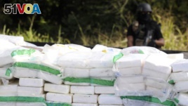 FILE - A police officer stands guard behind rows of confiscated drugs inside a military base in Santo Domingo.