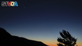 In this Sunday, Dec. 13, 2020 photo made available by NASA, Saturn, top, and Jupiter, below, are seen after sunset from Shenandoah National Park in Luray, Virginia, USA. (Bill Ingalls/NASA via AP)
