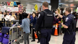 Police direct arriving passengers past dozens of pro-immigration demonstrators who cheer and hold signs at Dulles International Airport, to protest President Donald Trump's travel ban in Chantilly, Virginia, in suburban Washington, U.S., Jan. 29, 2017.