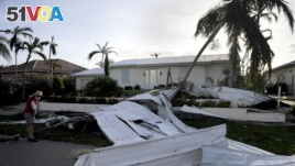 A roof is strewn across a home's lawn as Rick Freedman checks his neighbor's damage from Hurricane Irma in Marco Island, Fla., Sept. 11, 2017.