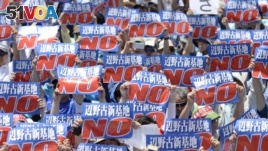 Protesters raise placards during a rally to oppose the transfer of a key U.S. military base within the prefecture, at a baseball stadium in the prefectural capital Naha on Japan's southern island of Okinawa, in this photo taken by Kyodo May 17, 2015. The Navy has received increased pressure in Okinawa where residents are calling for the removal of U.S. bases. American military arrests help the Japanese argument.