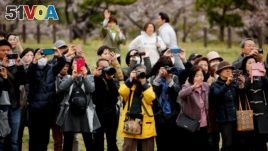 Fumiko Shirataki and well-wishers try to take photographs of Japan's Emperor Akihito and Empress Michiko