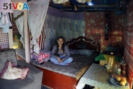 In this Tuesday, Dec. 12, 2017 photo, Renata Swiecik sits on a bed inside her shack