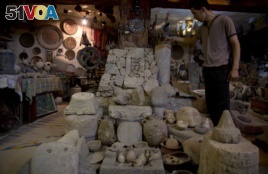In this July 17, 2019 photo, a Palestinian looks at ancient artifacts displayed inside the Shahwan private museum in the basement of a building, in Khan Younis, Southern Gaza Strip.
