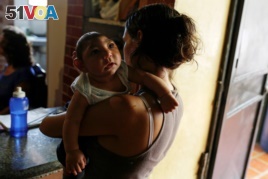 FILE - Ericka Torres holds her 3-month-old son, Jesus, who was born with microcephaly, at their home in Guarenas, Venezuela, Oct. 5, 2016.