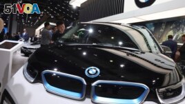 FILE - In this Wednesday, April 17, 2019 file photo, a worker cleans an electric vehicle at the BMW booth during the Auto Shanghai 2019 show in Shanghai. 
