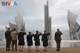 Enthusiasts of England salute in front of The Brave, a monument dedicated to the American soldiers who landed on Omaha Beach on D-Day, in Saint-Laurent-sur-Mer, Tuesday, June 4, 2019, in Normandy.