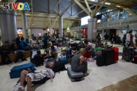 Foreign tourists sleep on the floor as they wait to depart from the Praya Lombok International Airport on the West Nusa Tenggara province on August 6, 2018.