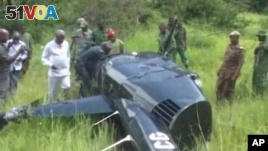 Tanzanian officials walking towards a downed helicopter. The pilot was shot down by poachers he chased. (ITV Tanzania via AP)