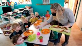 Amy McCoy serves lunch to preschoolers at her Forever Young Daycare facility, Monday, Oct. 25, 2021, in Mountlake Terrace, Wash. (AP Photo/Elaine Thompson)