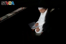 FILE - Abdul Barek Hajji, a Bengali Muslim, reads the Koran while waiting for the Maghrib sunset prayer during Ramadan at the Abu Bakr Mosque in Flushing, New York, May 31, 2017.