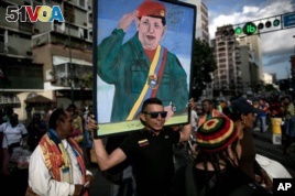 A government supporter carries a painting of Venezuela's late President Hugo Chavez in Caracas, Venezuela, Tuesday, Jan. 5, 2016, to protest the swearing-in of opposition lawmakers.  (AP Photo/Alejandro Cegarra)