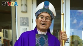 FILE - Archbishop Anthony Apuron stands in front of the Dulce Nombre de Maria Cathedral Basilica in Hagatna, Guam, in November 2014.