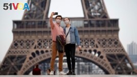 People take a selfie in front of the Eiffel Tower in 2020. A new French dictionary came out, supporting the way the language is spoken outside of France for the first time. (REUTERS/Gonzalo Fuentes)