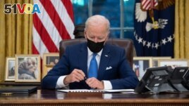 FILE - US President Joe Biden signs executive orders related to immigration in the Oval Office of the White House in Washington, DC, February 2, 2021. (Photo by SAUL LOEB / AFP)
