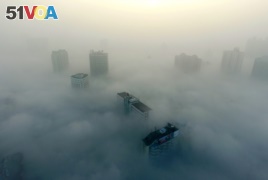 FILE - Buildings are seen on a hazy day in Xiangyang, Hubei province, China, Dec. 31, 2016.