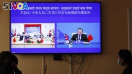 Nepalese government officers watch a live telecast of a joint announcement on the height of Mount Everest, in Kathmandu, Nepal, Tuesday, Dec. 8, 2020. China and Nepal have jointly announced on Tuesday, Dec. 8, 2020, a new height for Mount Everest, ending