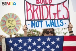 Lauren Rees holds up a sign during a rally against a scheduled visit by President Donald Trump, March 13, 2018, in San Diego.
