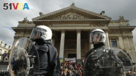Police in riot gear protect one of the memorials to the victims of the recent Brussels attacks, as right wing demonstrators protest near the Place de la Bourse in Brussels, Sunday, March, 27, 2016.