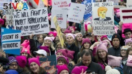 FILE - Women with pink hats and signs protested on the first full day of Donald Trump's presidency, Jan. 21, 2017 in Washington. Discussions about the Women's March on Washington and other locations sent many people to look up 