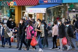 FILE - In this March 30, 2021, file photo, people cross a busy street in the shopping district of Flushing, a largely Asian American neighborhood in the Queens borough of New York. (AP Photo/Kathy Willens, File)