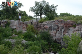 Mikah stands above a pipestone quarry. Native Americans use the red stone to make ceremonial pipes.